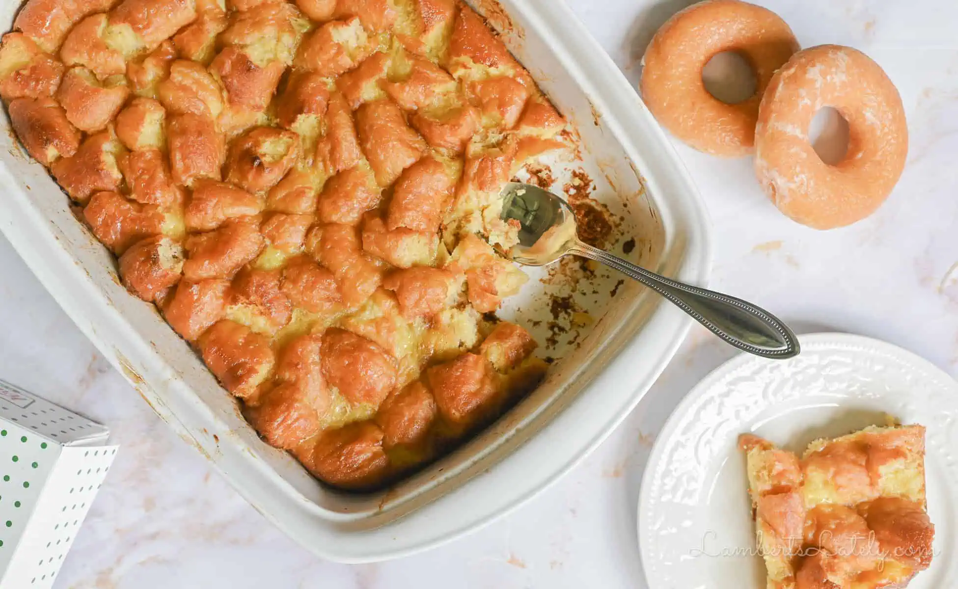 donut bread pudding in a casserole dish, with plate with a serving and donuts next to it.