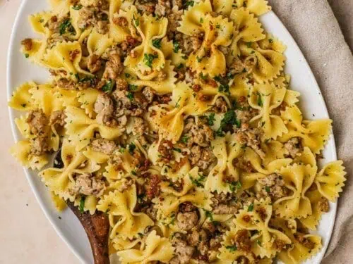 Chicken sausage pasta in a serving dish with a wooden spoon.