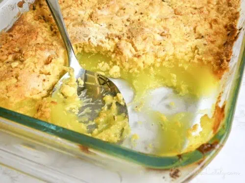 a spoon in a baking dish of lemon dump cake.