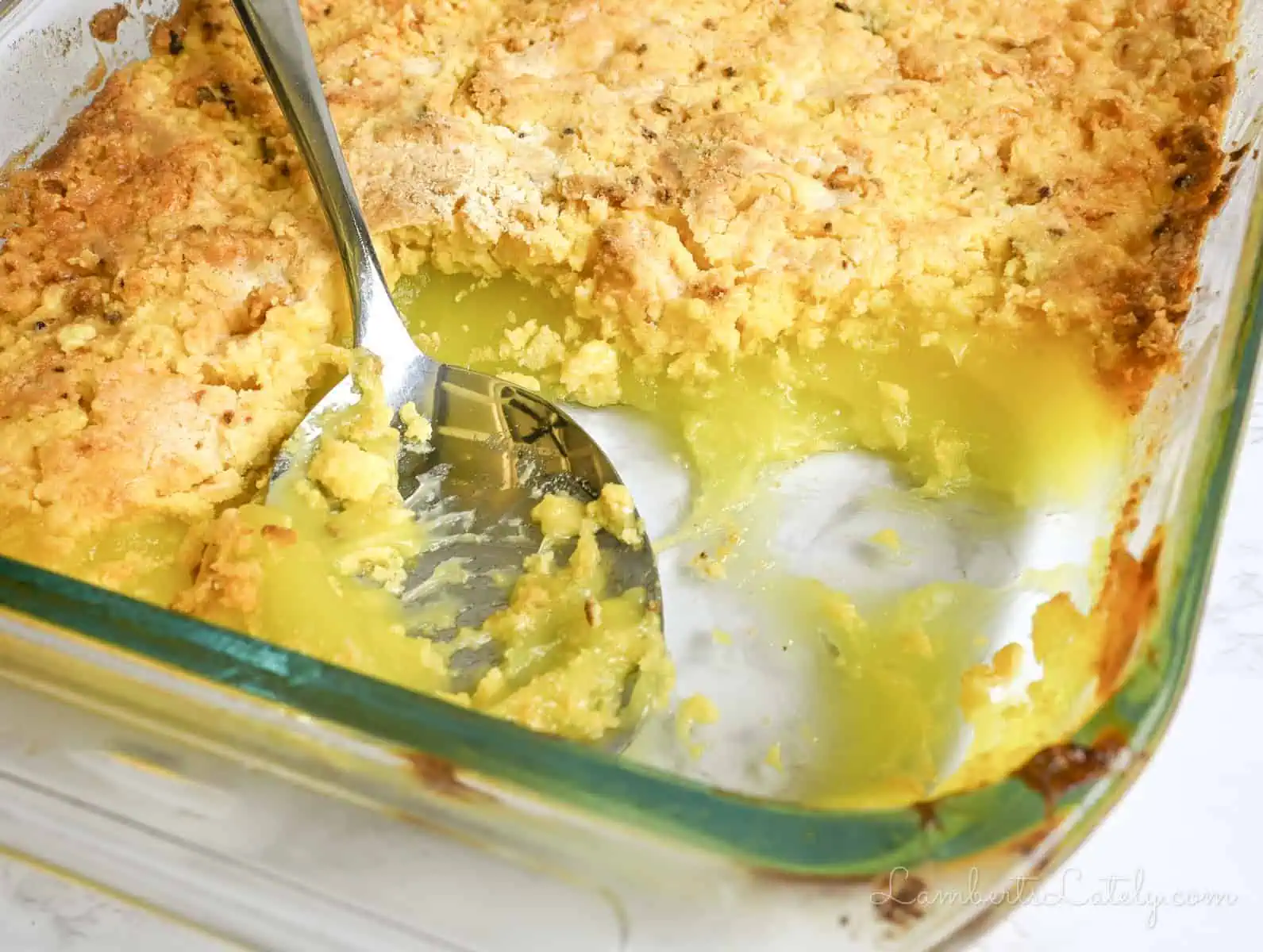 a spoon in a baking dish of lemon dump cake.