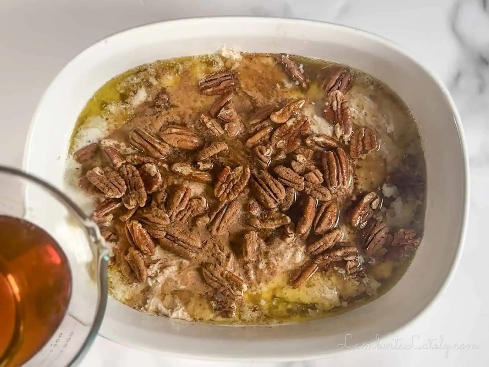 pouring brown sugar syrup over pecans, cake mix, and butter.