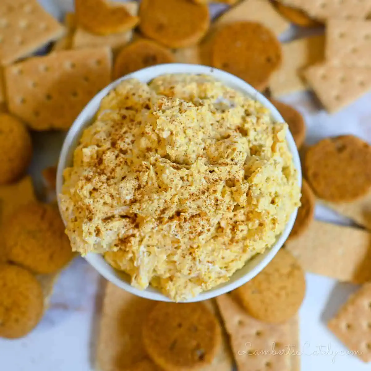 bowl of pumpkin fluff dip surrounded by graham crackers and ginger snaps.