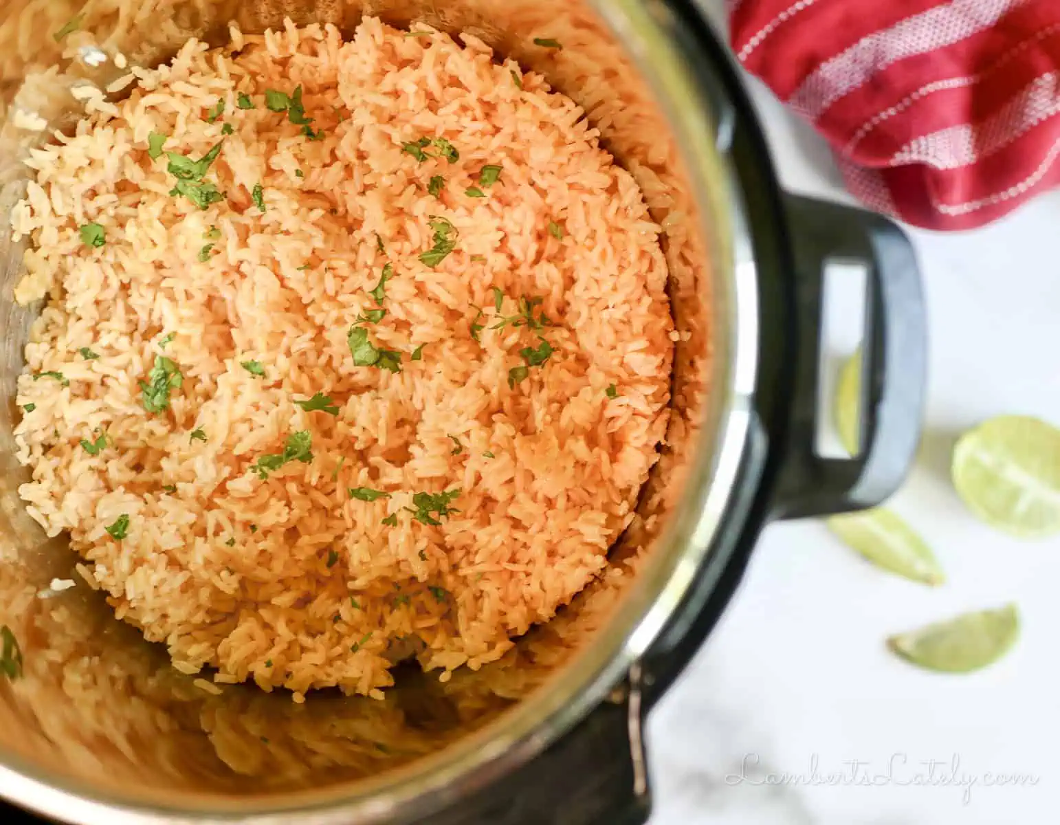 mexican rice topped with cilantro in an instant pot, with limes and a towel next to it.