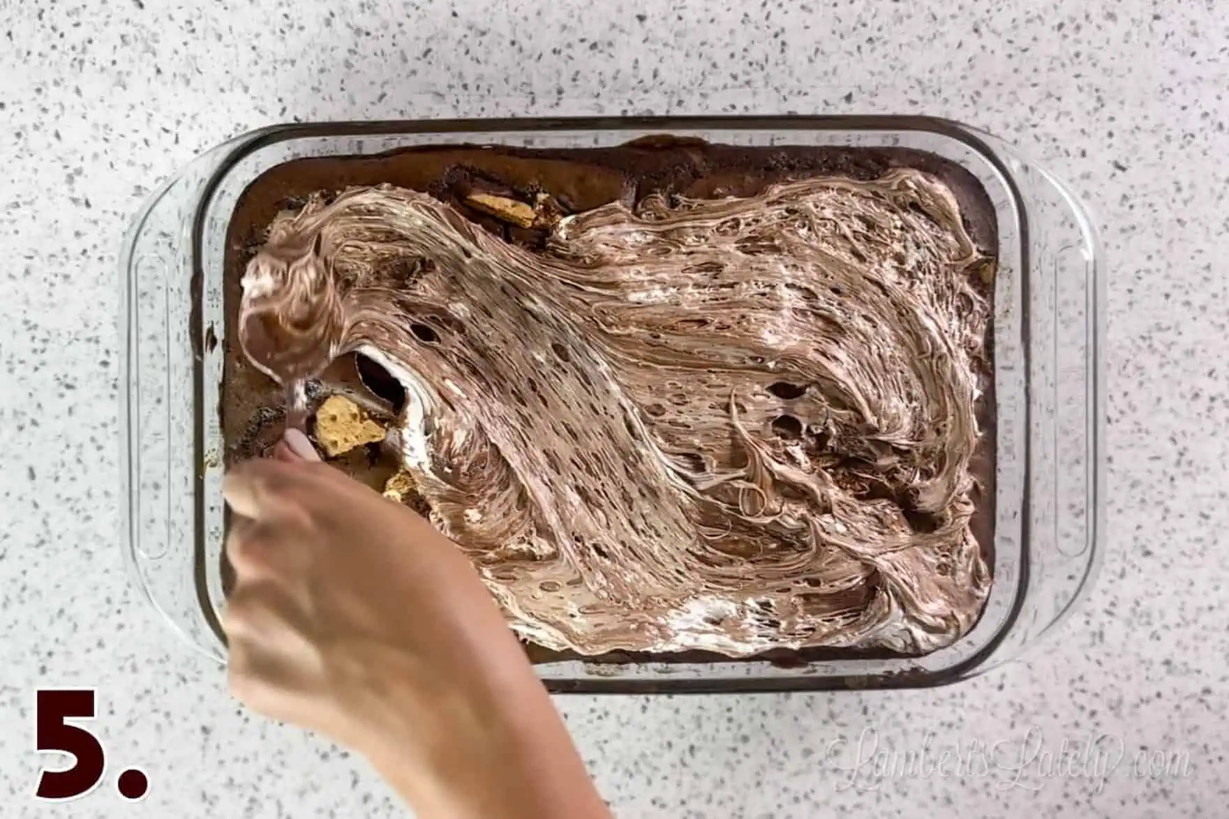 spreading chocolate marshmallow fluff on smores cake.