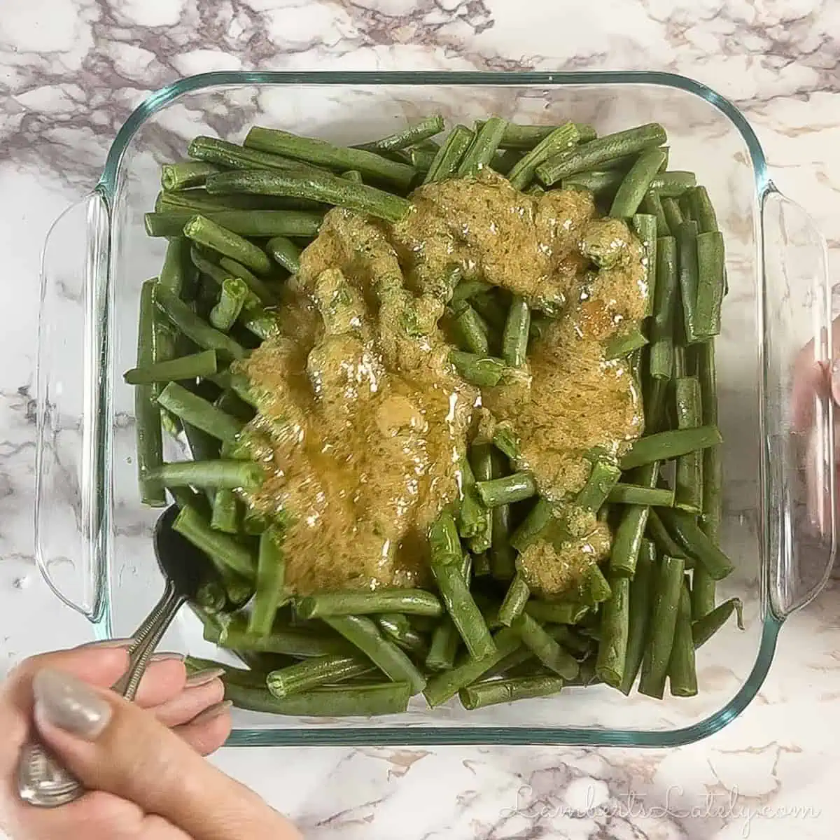 pouring sauce over green beans in the baking dish.