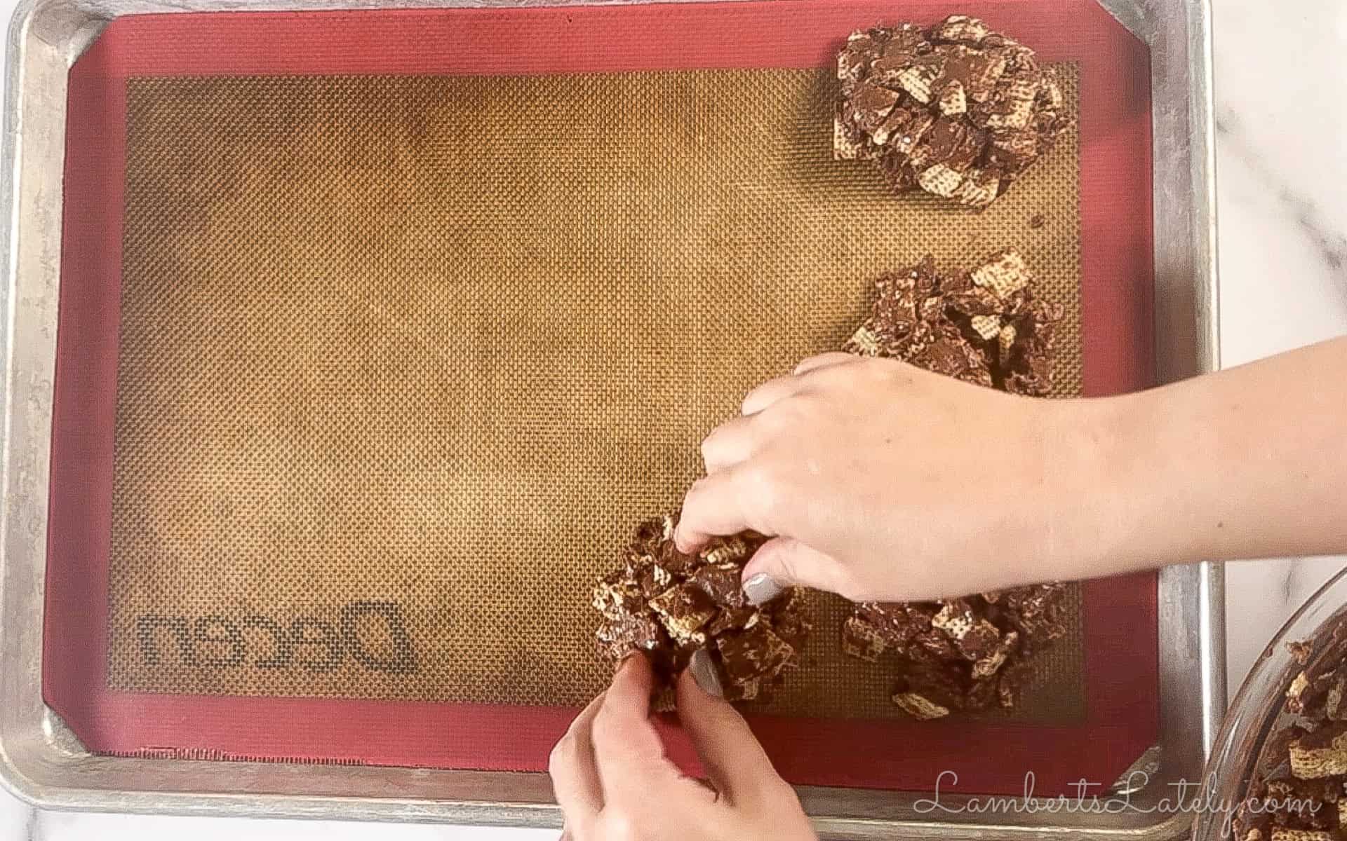 forming chocolate chex mixture into cookies on a baking sheet.