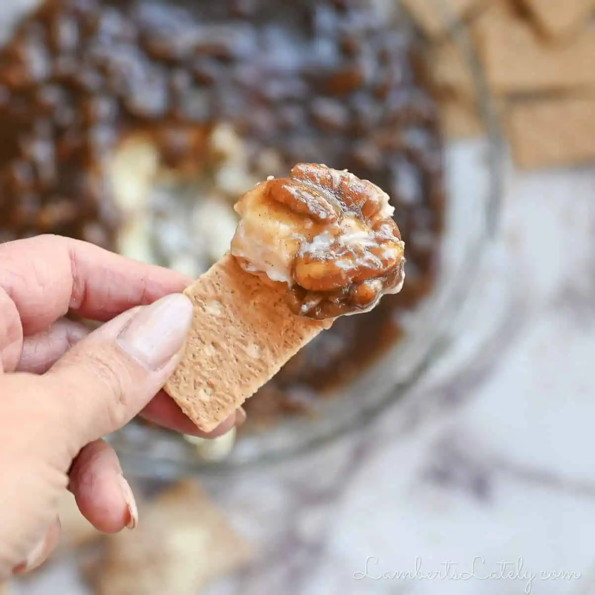 holding pecan pie dip on a graham cracker.
