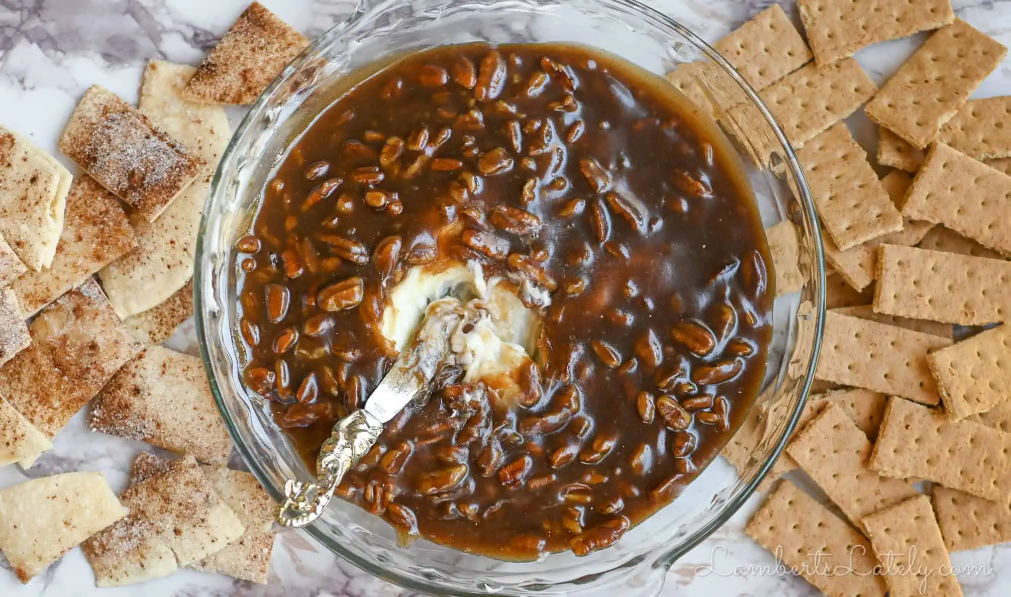 pecan pie dip in a pie dish, with a knife, surrounded by dippers.