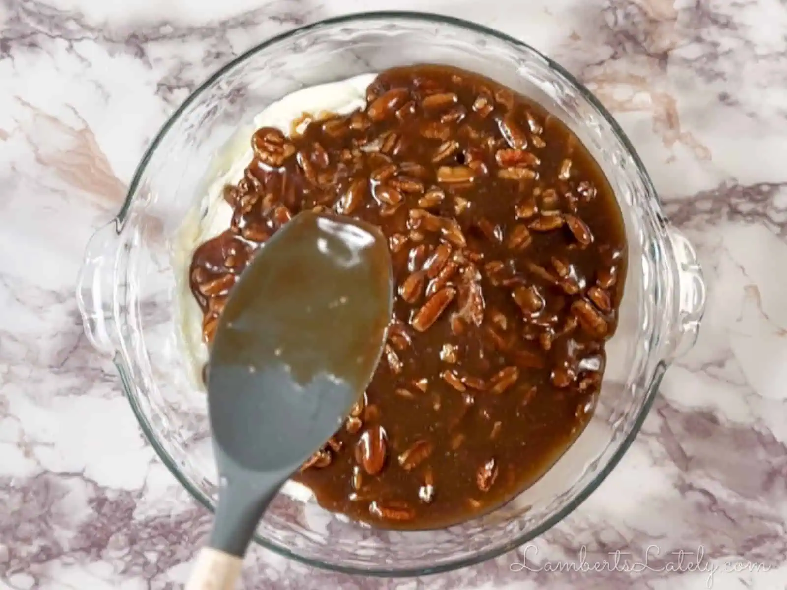 spreading pecan pie mixture over the cream cheese base in the pie dish.