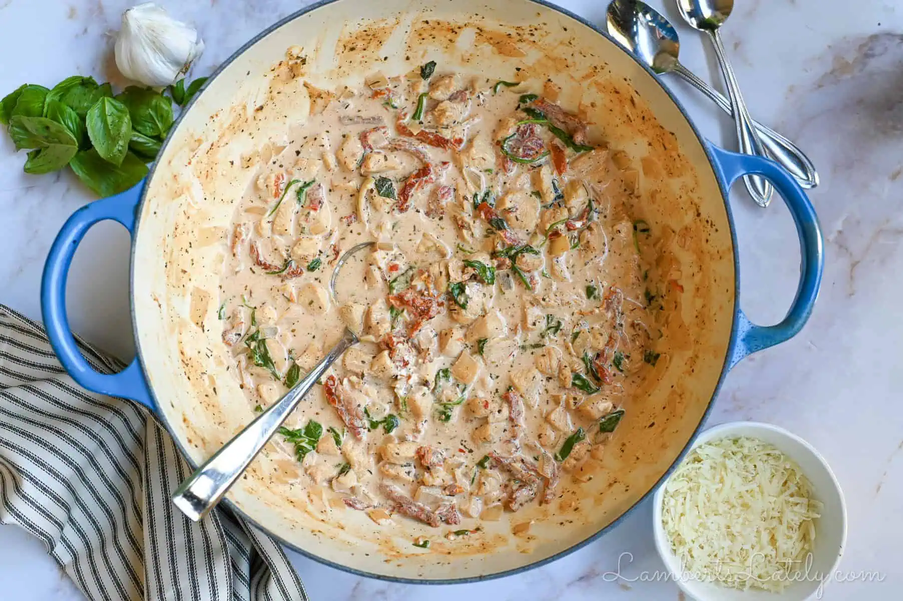 marry me chicken soup in a large pot, surrounded by bowls of parmesan cheese, basil, garlic.
