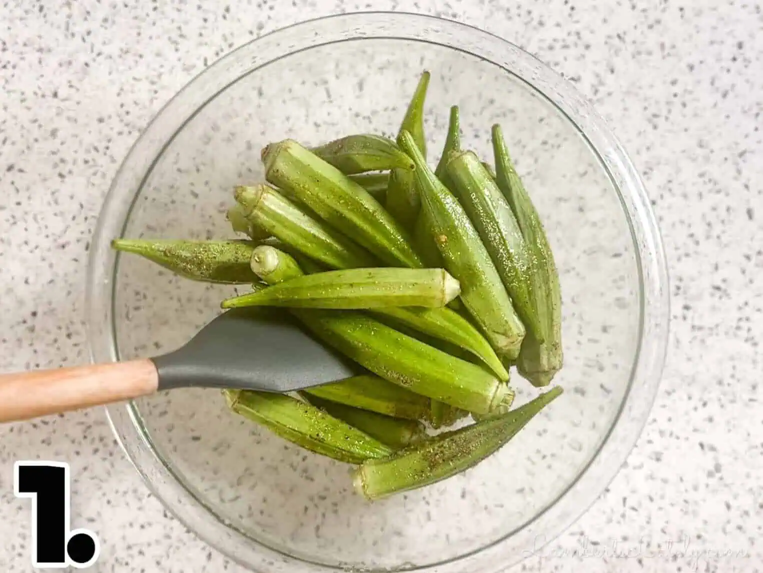 stirring okra with oil and seasonings in a bowl.