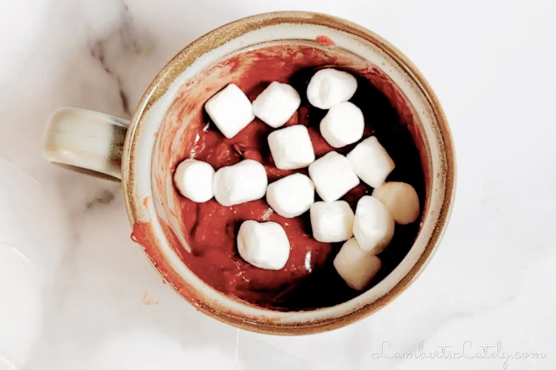marshmallows on top of hot chocolate cake batter in the mug.