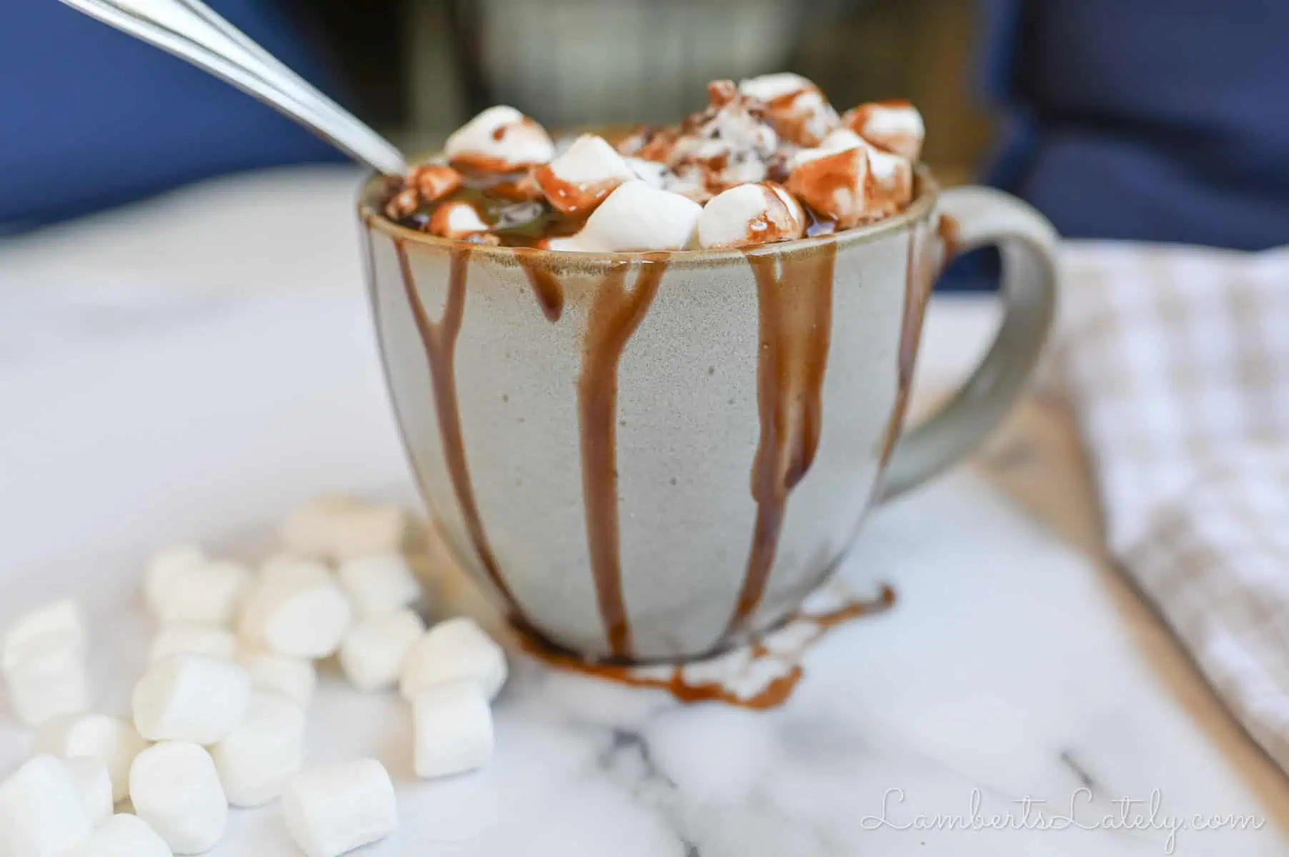 hot chocolate mug cake in a mug, chocolate syrup running down mug, covered in marshmallows.