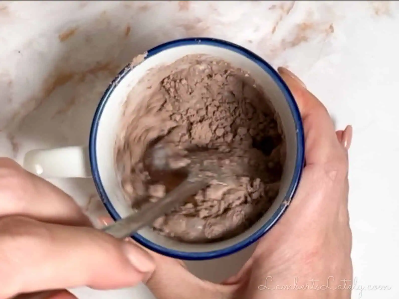 stirring mug cake ingredients together in a coffee cup.