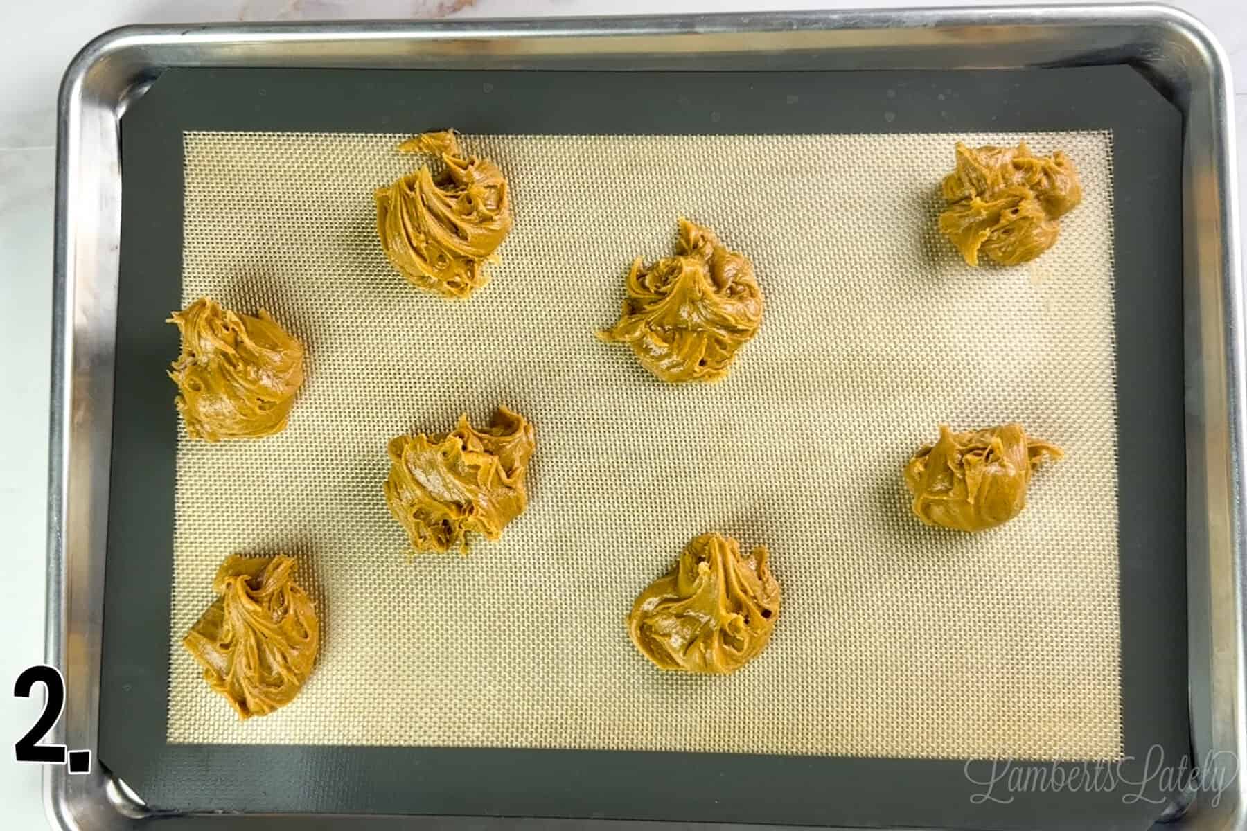 peanut butter cookie dough spooned onto a baking sheet.
