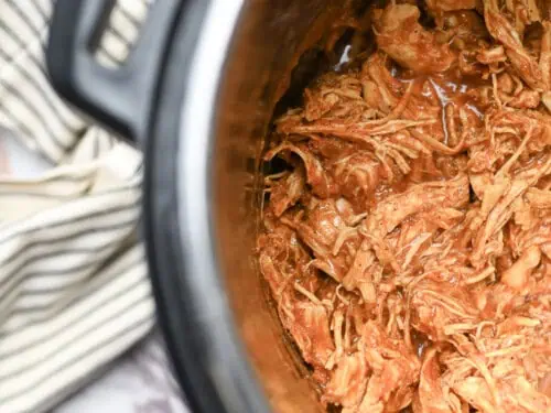 barbecue chicken covered in sauce in an instant pot, towel beside it.