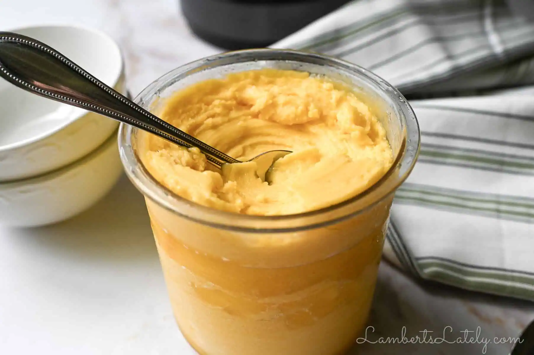 bowl of ninja creami mango sorbet with a spoon in it, napkin, stack of bowls.