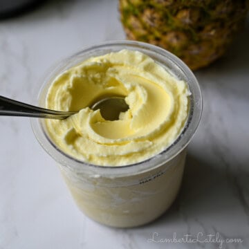 pint of pineapple dole whip with a pineapple in the background.