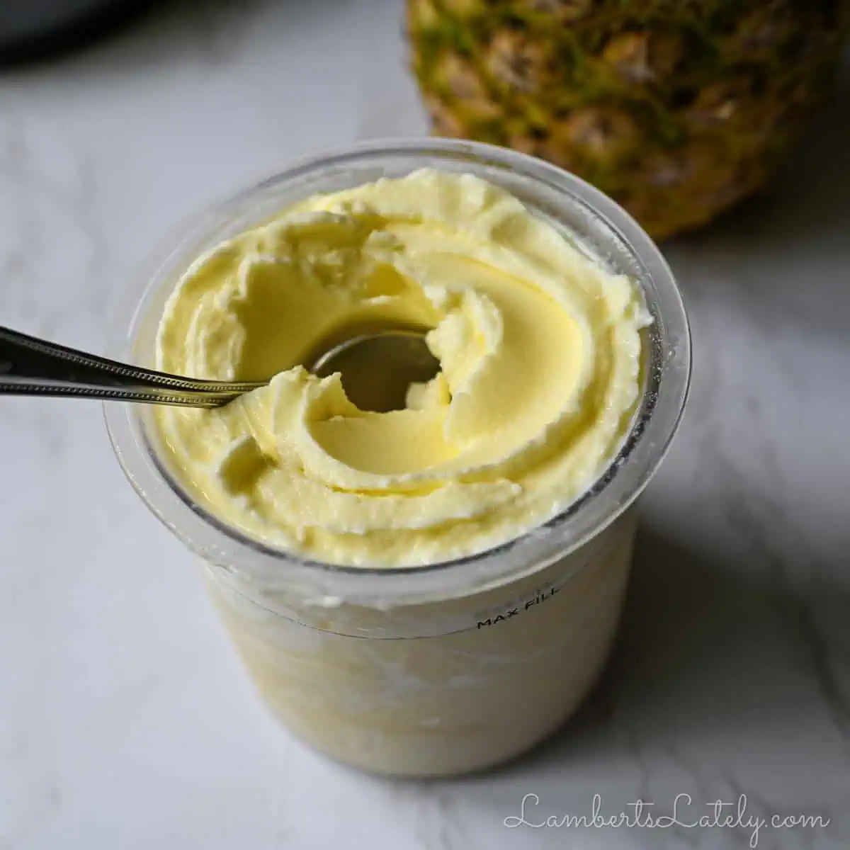 pint of pineapple dole whip with a pineapple in the background.