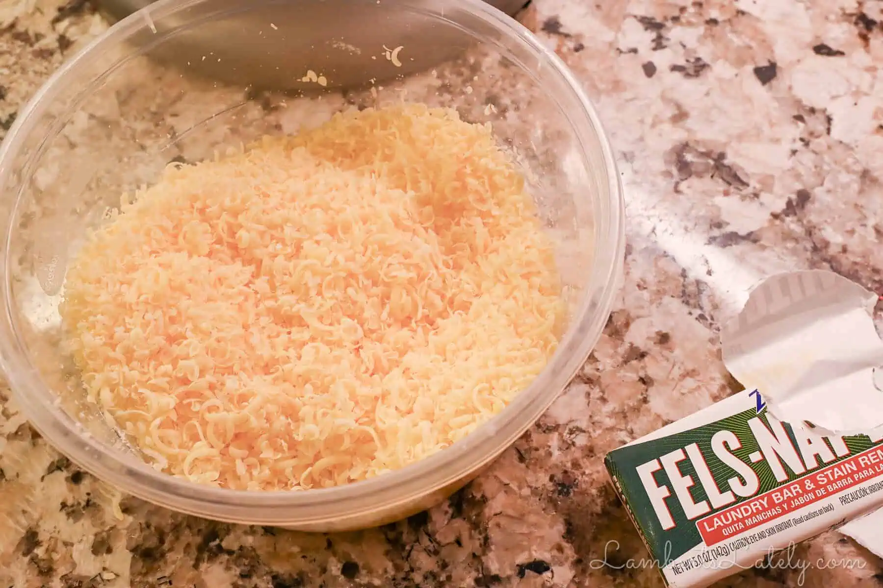 grated fels naptha soap in a container on a counter, next to a soap wrapper.
