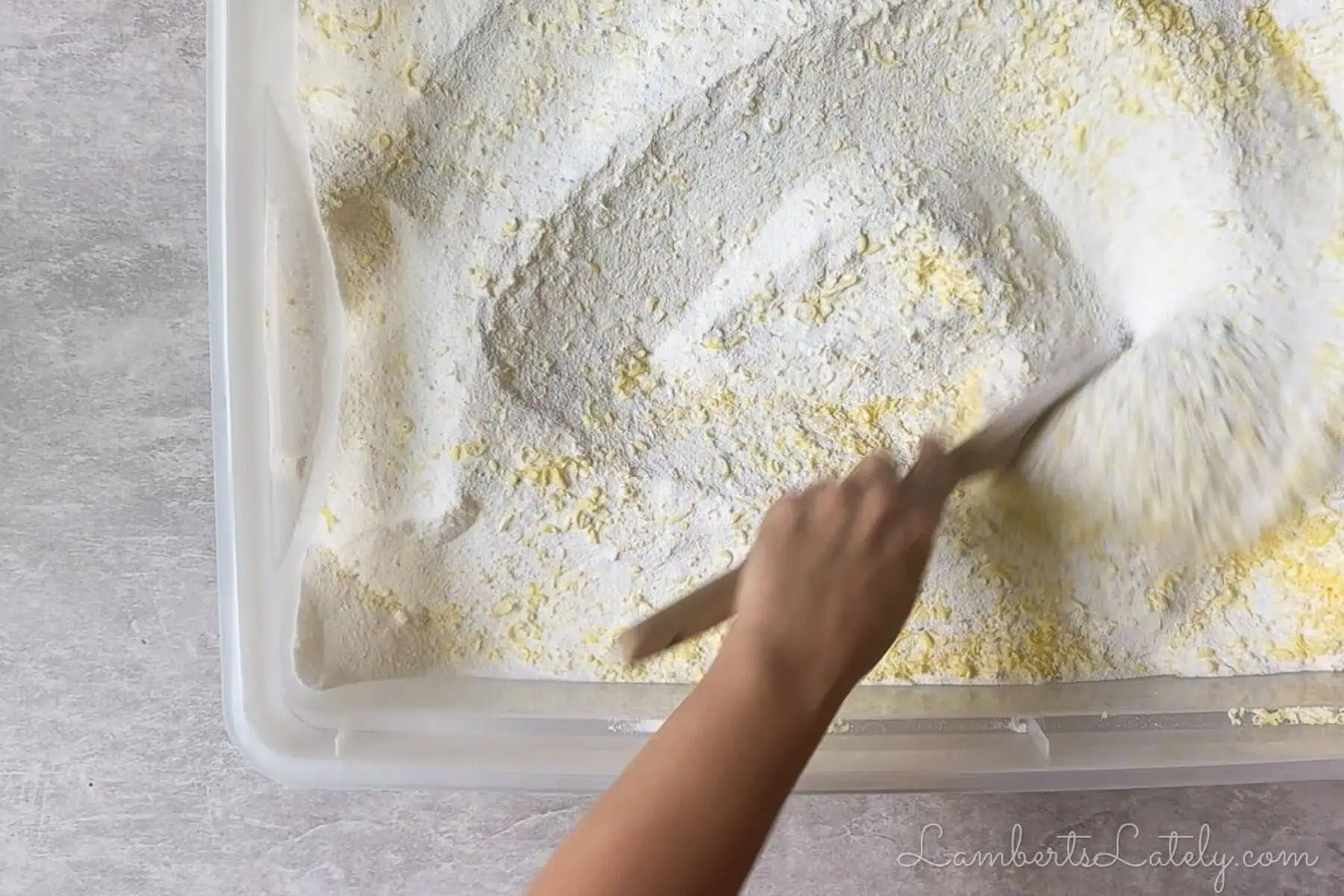 stirring diy laundry detergent together with a wooden spoon.