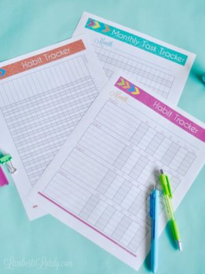 three colorful habit logs next to pens.