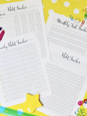 habit tracking printables spread out around office supplies.