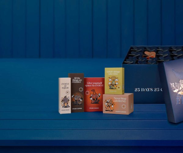 Orange, white, red, yellow y rosa fondos con empaques de cartón con mensajes motivadores y personajes de dibujos animados. Caja azul con monogramas y hojas doradas y plateadas en fondo azul con láminas verticales.