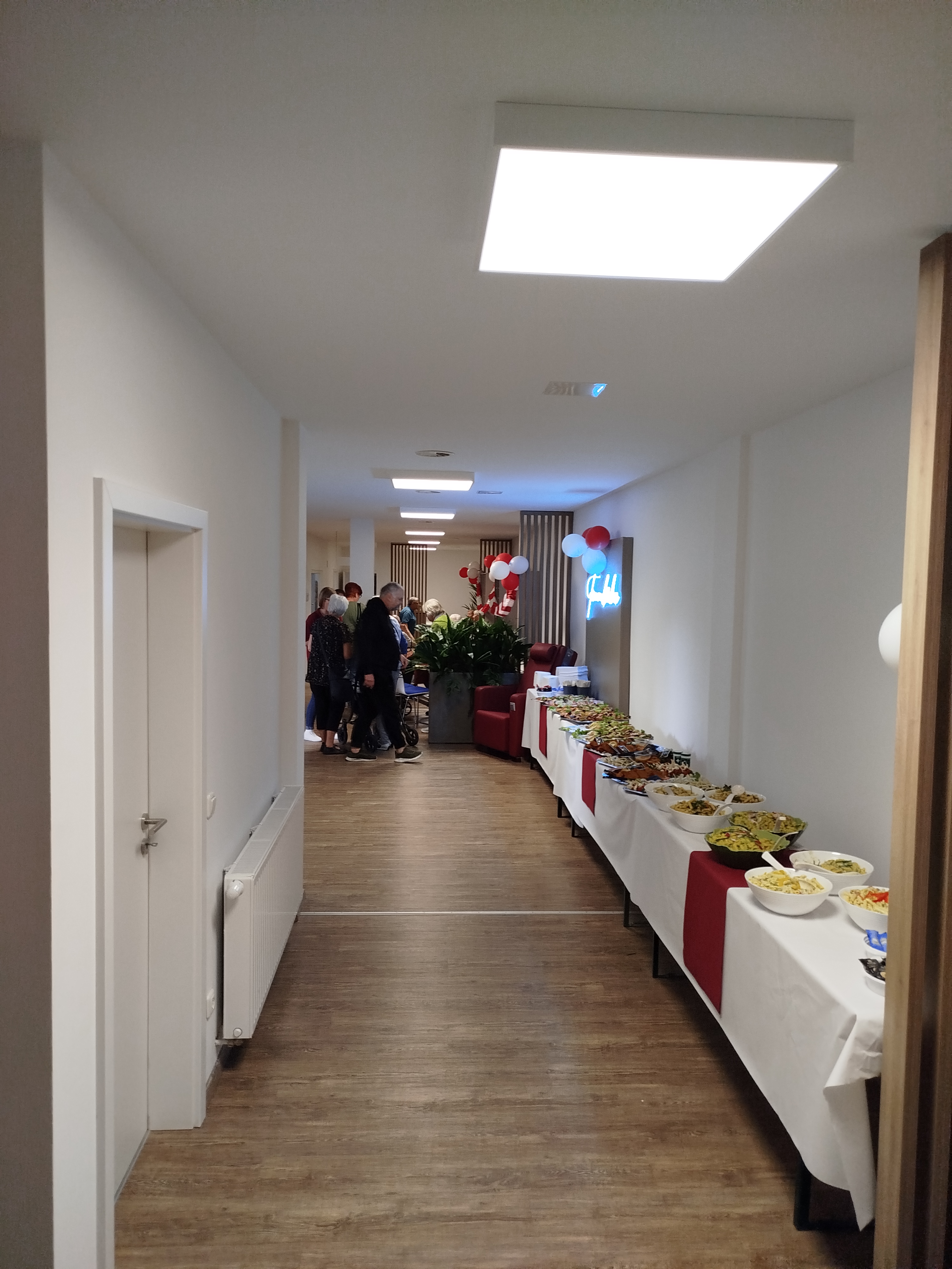 Heller Veranstaltungsraum Lindweiler mit Buffet und Dekorationen, ideal für Feiern und Events, modernes Design, freundliche Atmosphäre und mehrere Gäste im Hintergrund.
