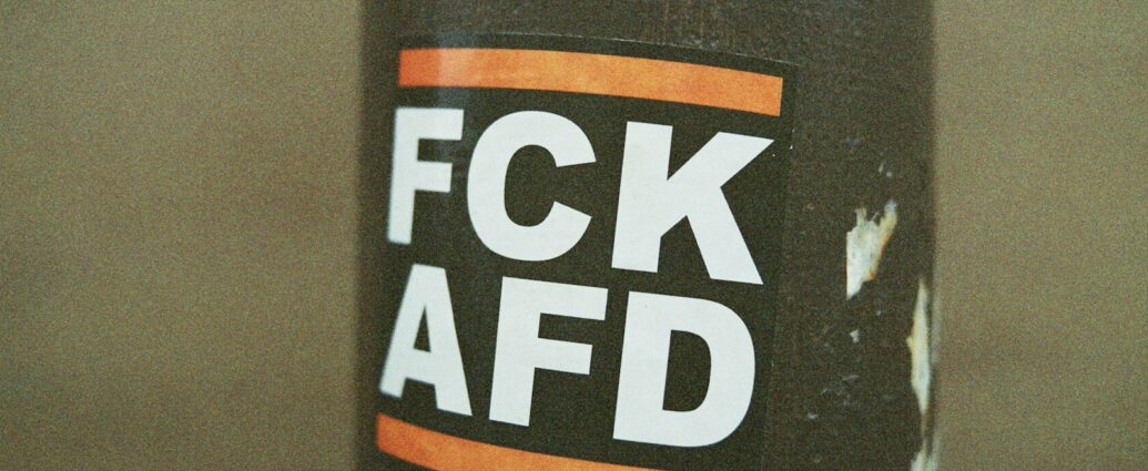 Verbotsschild mit schwarzem Hintergrund und weißen Buchstaben, inklusive orangefarbenen Balken oben und unten.