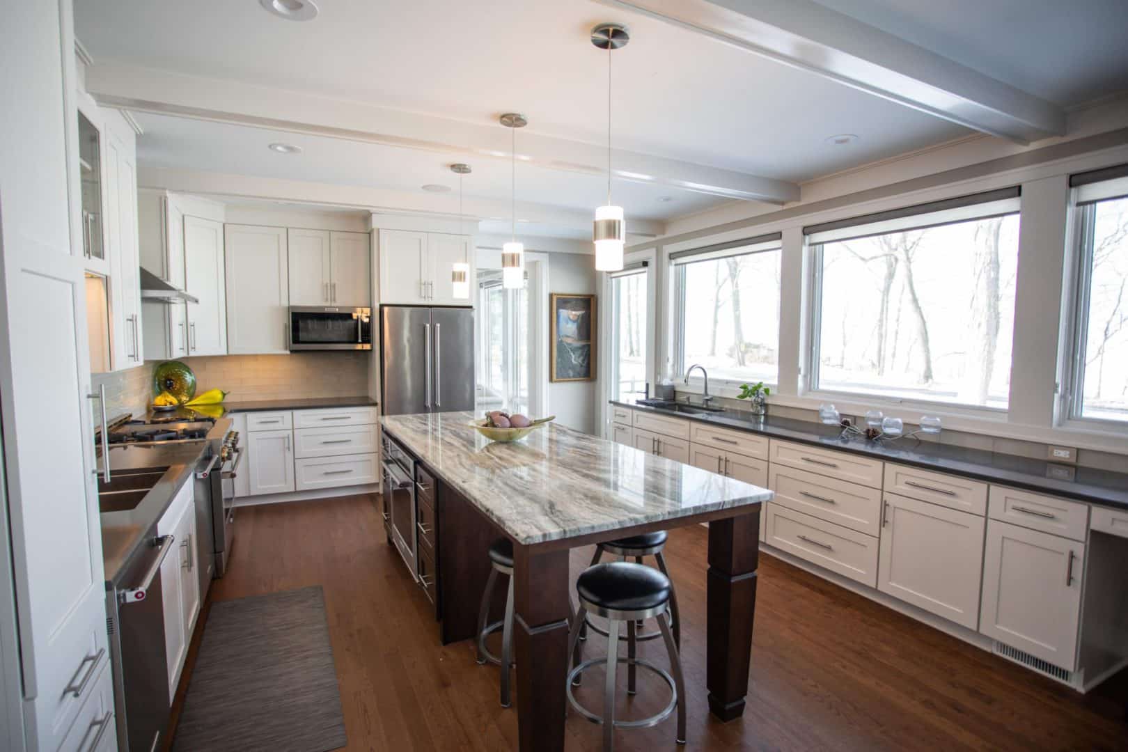 Livingston Homes kitchen featuring a spacious island, white cabinetry, and large windows for bright,.