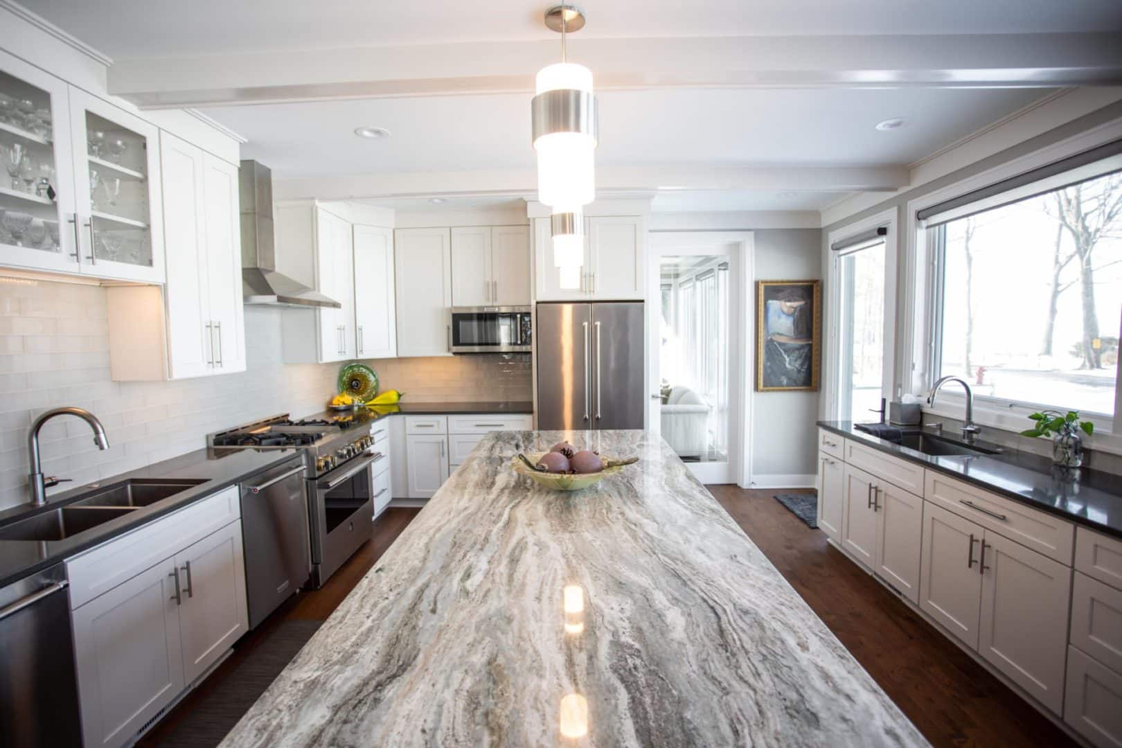 Bright, spacious kitchen featuring white cabinetry, a large central island, stainless steel applianc.