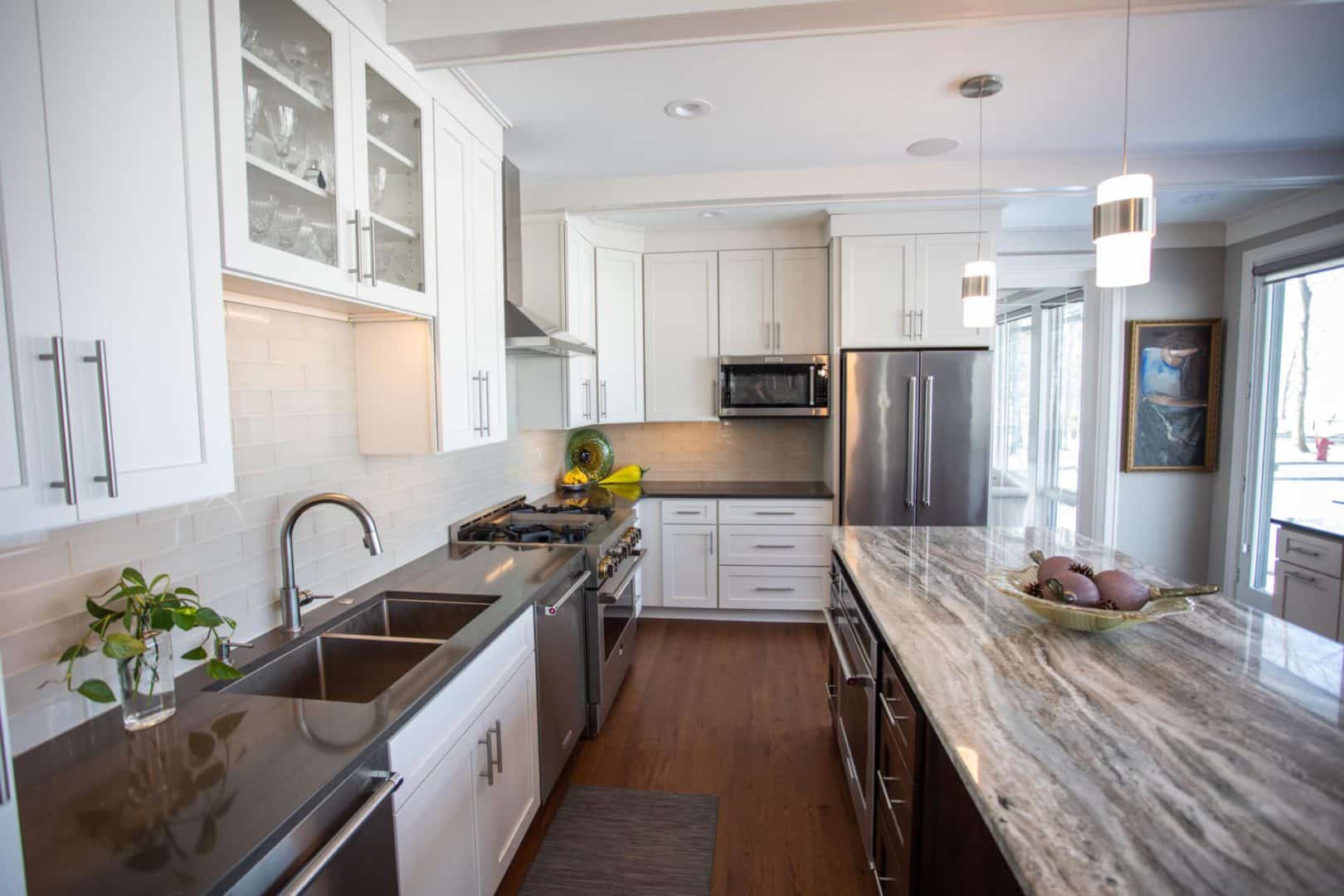 Kitchen with white cabinets, stainless steel appliances, and a large granite island.
