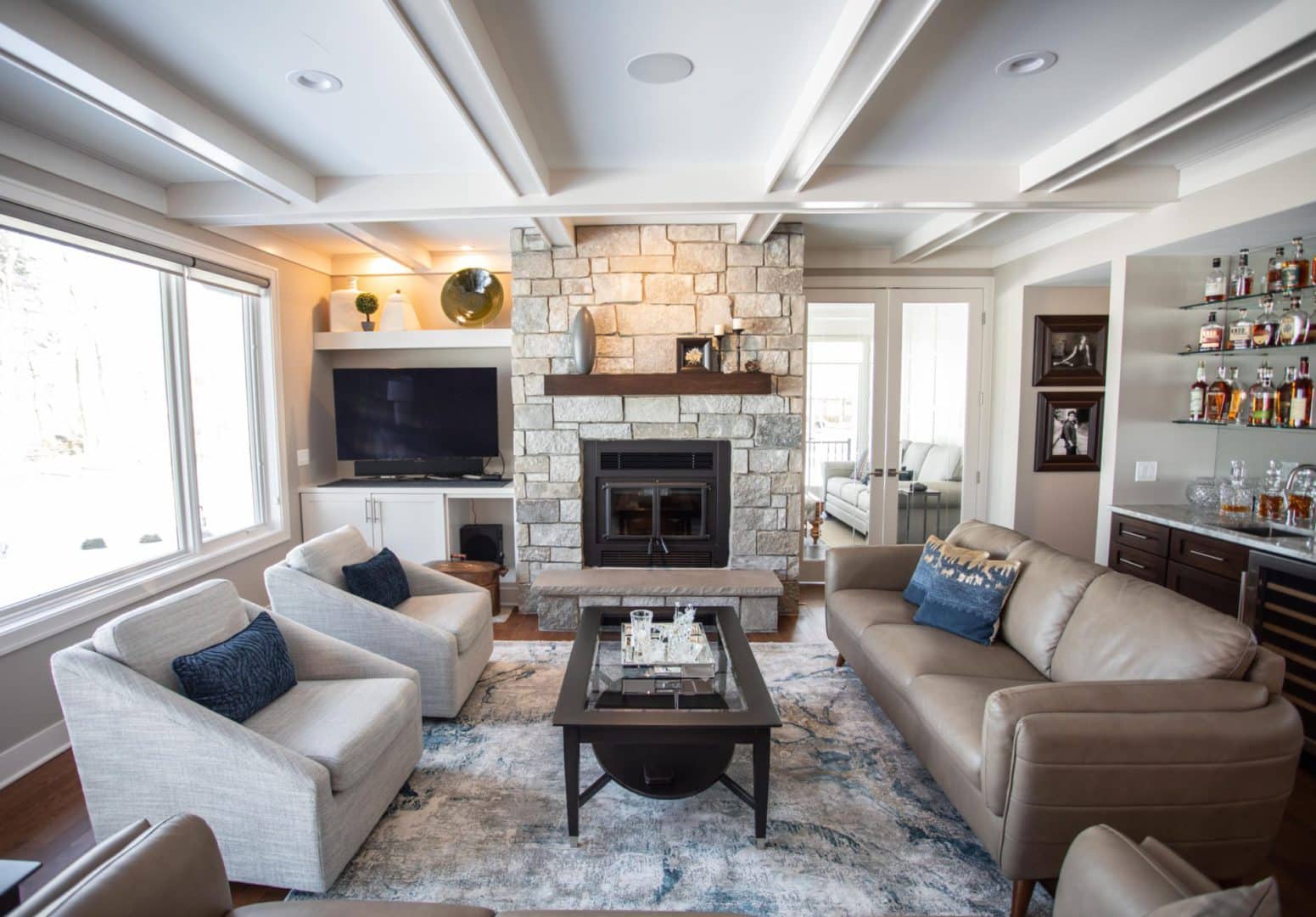 Living room with stone fireplace, modern furniture, and large windows.