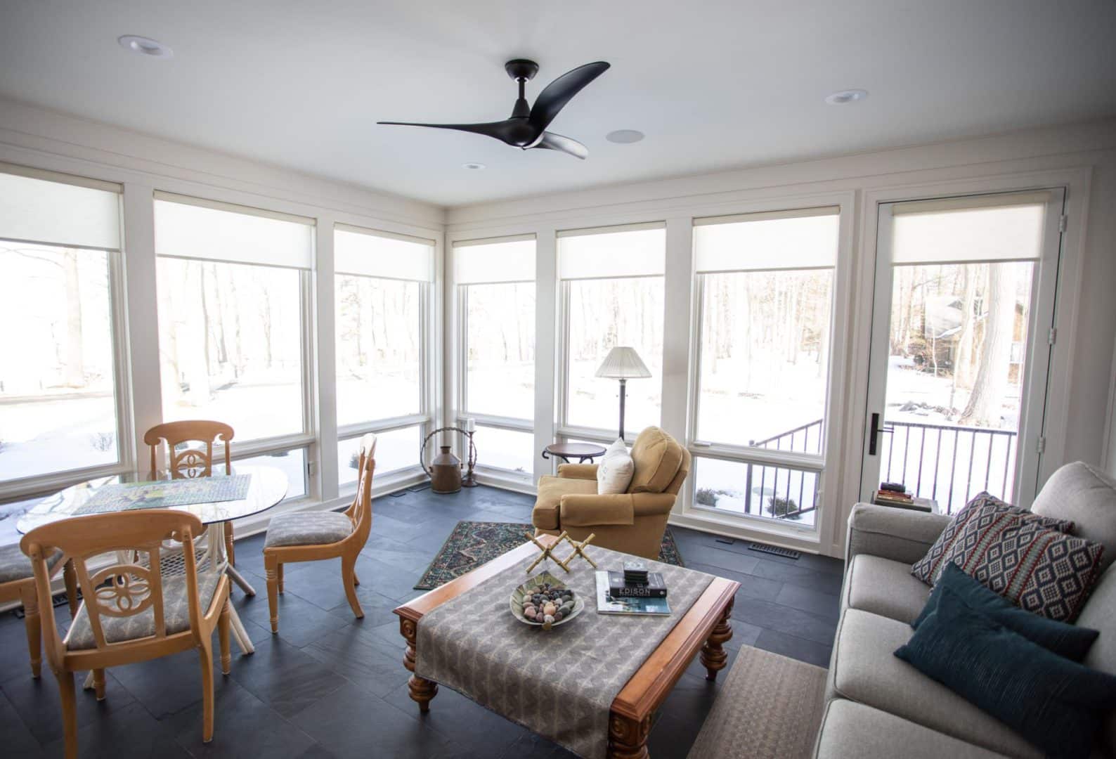 Sunroom with large windows and modern ceiling fan.
