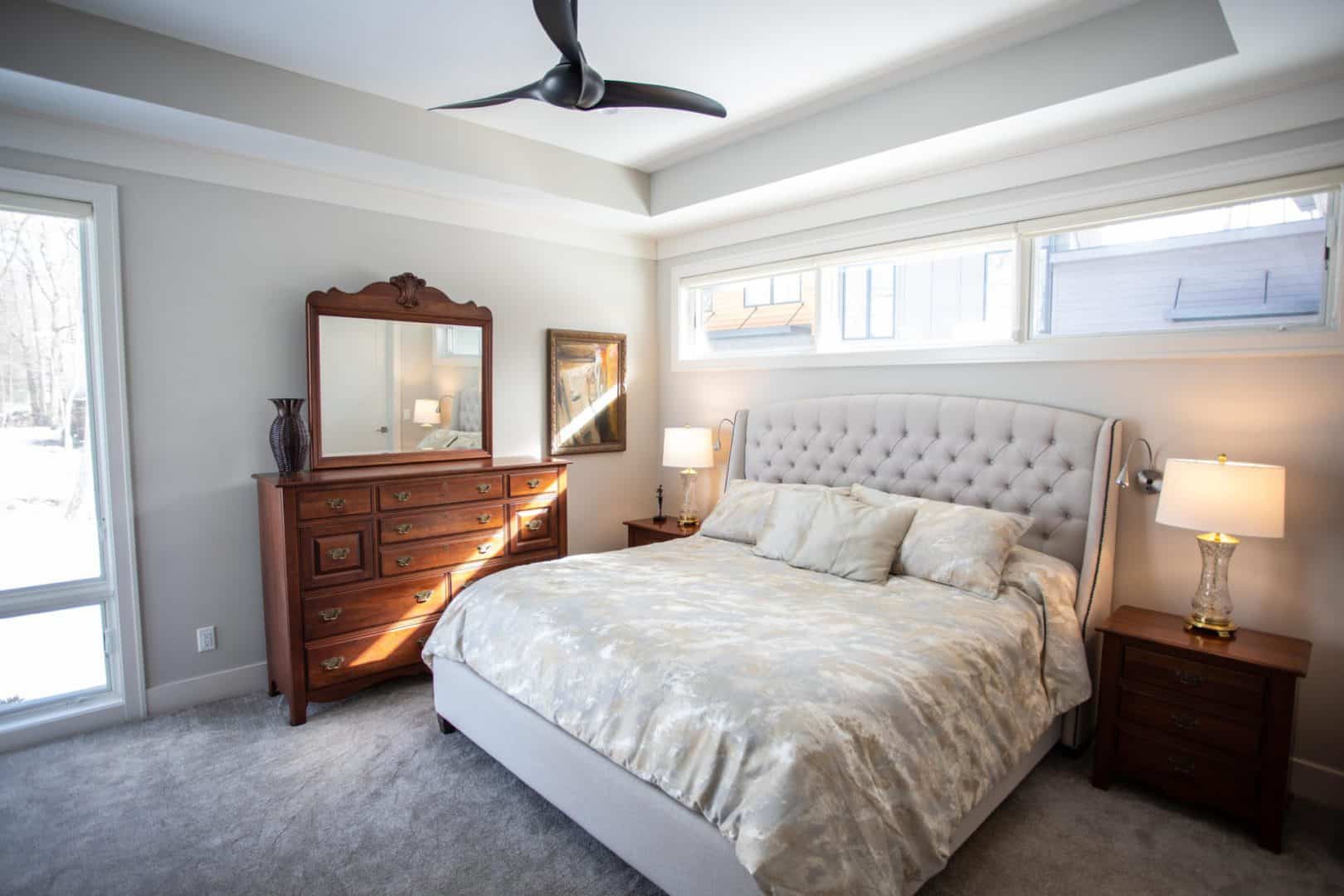 Spacious bedroom featuring a large bed, stylish furniture, and natural light from expansive windows.