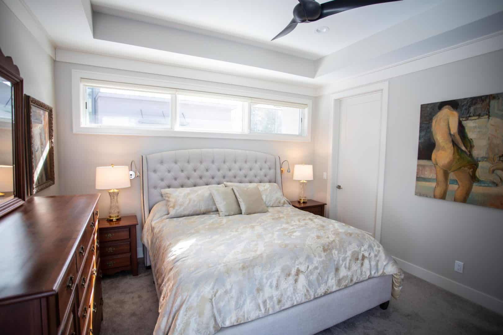 Modern bedroom with a tufted headboard and large window for natural light.