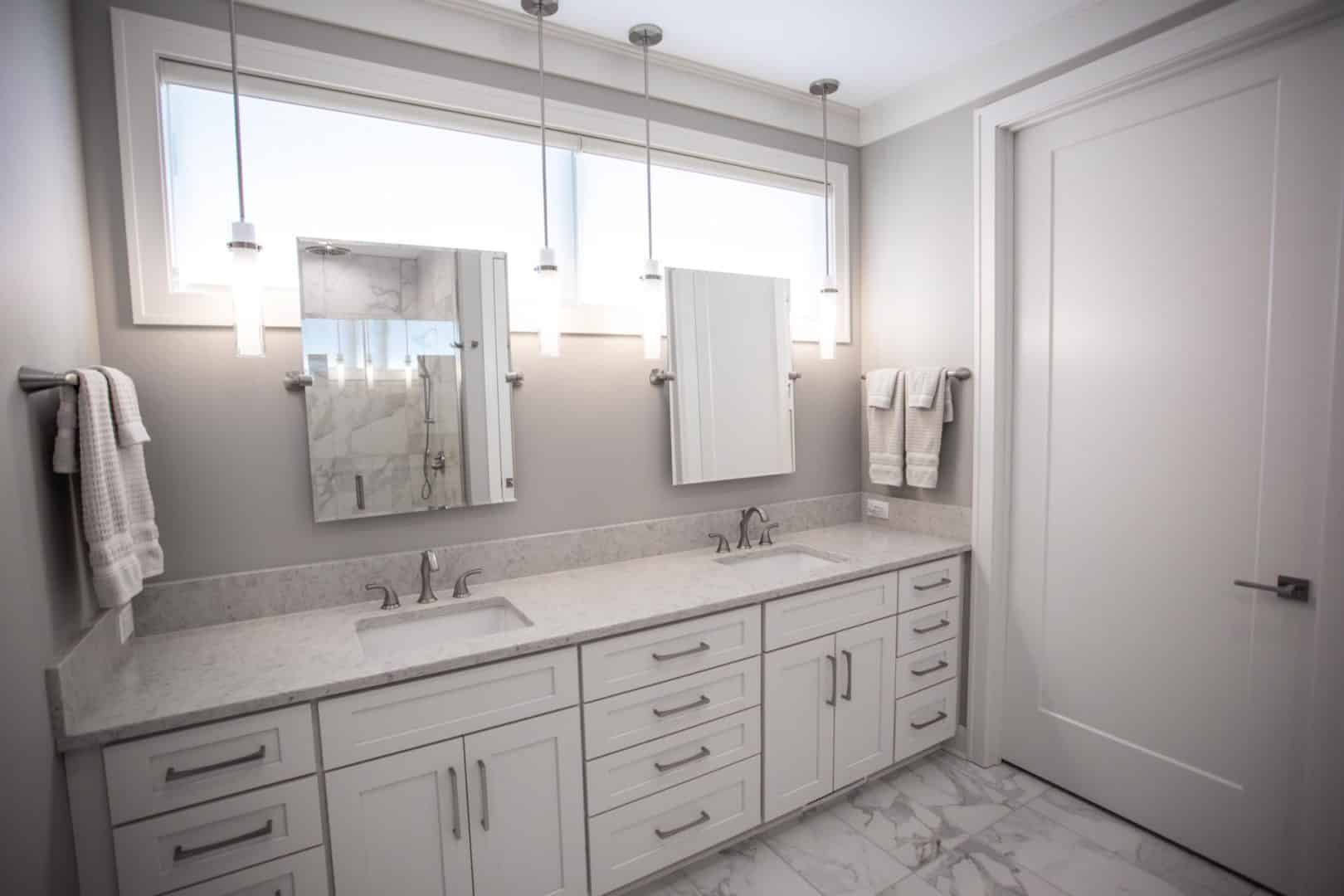 Bright modern bathroom with white vanity, double sinks, and large windows for natural light.