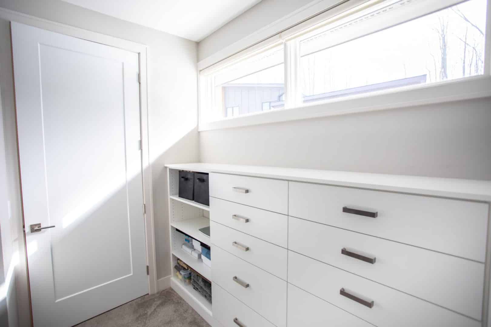 Interior laundry room with white cabinets and large window.