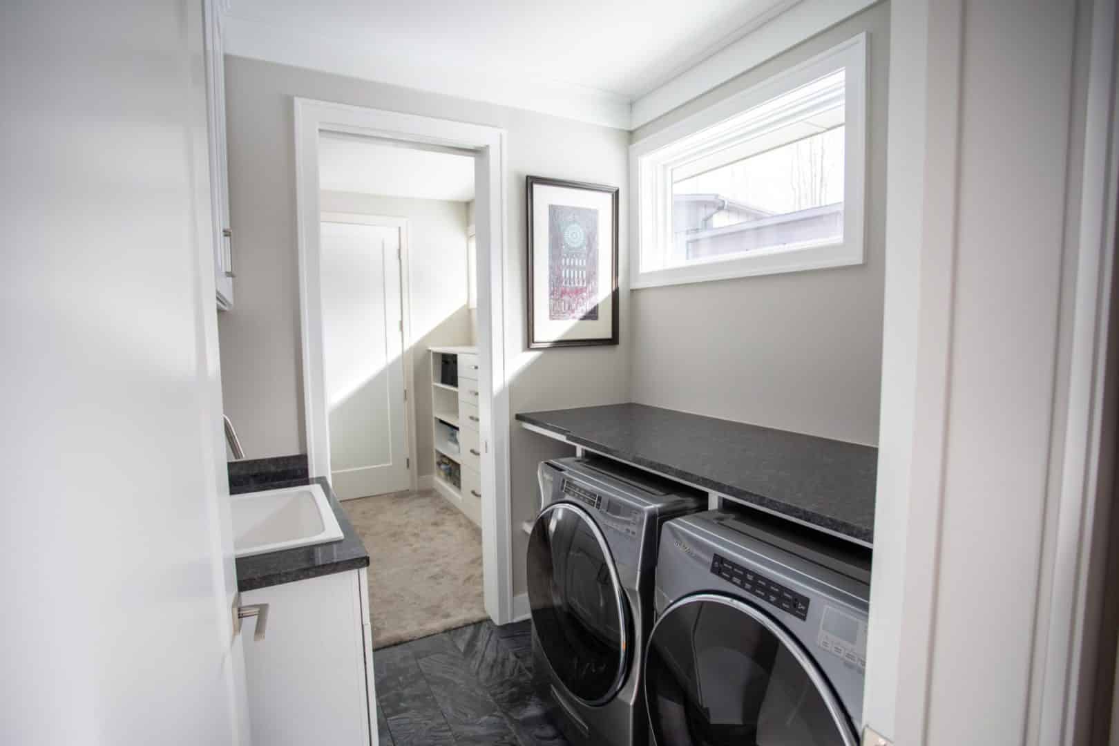 Modern laundry room with washer and dryer, bright natural light, and storage space.