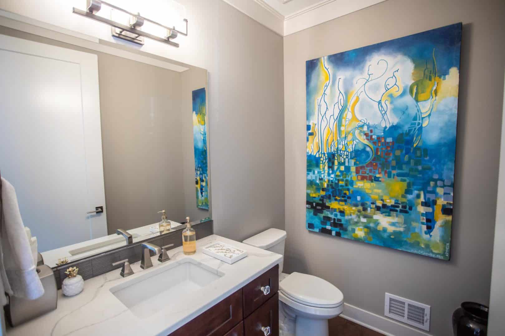 Bathroom with modern vanity and colorful abstract art.