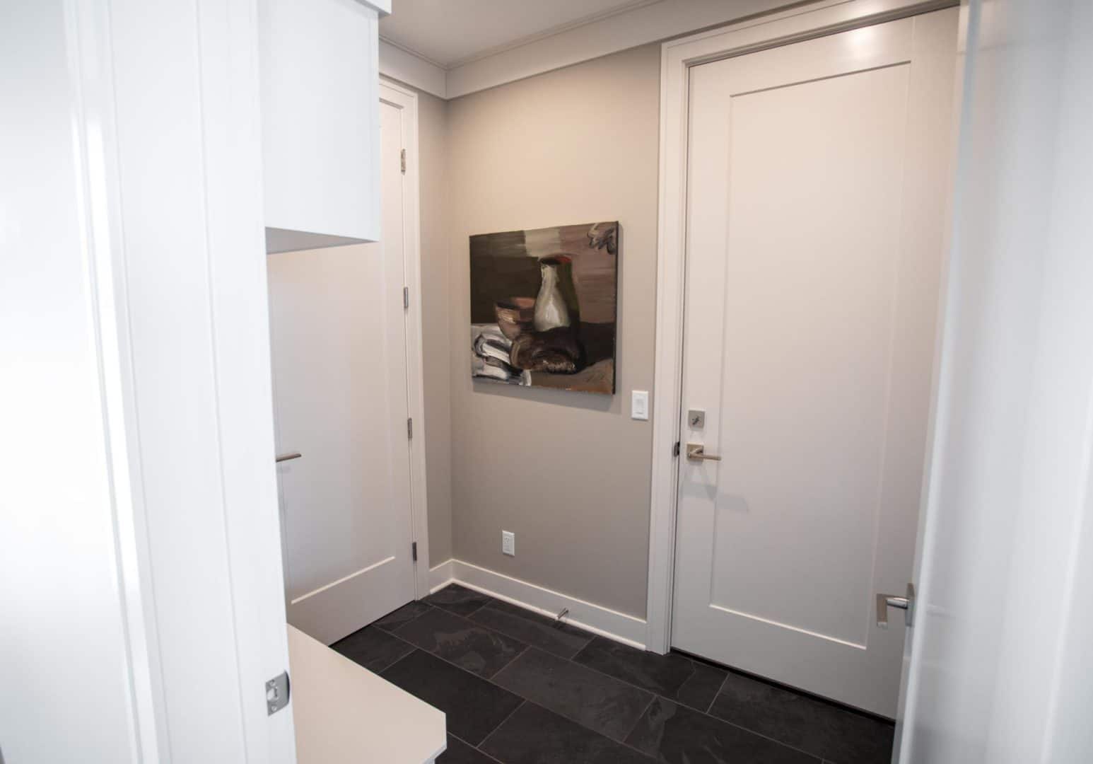 Entryway of a modern home featuring neutral-colored walls, white doors, and contemporary artwork.