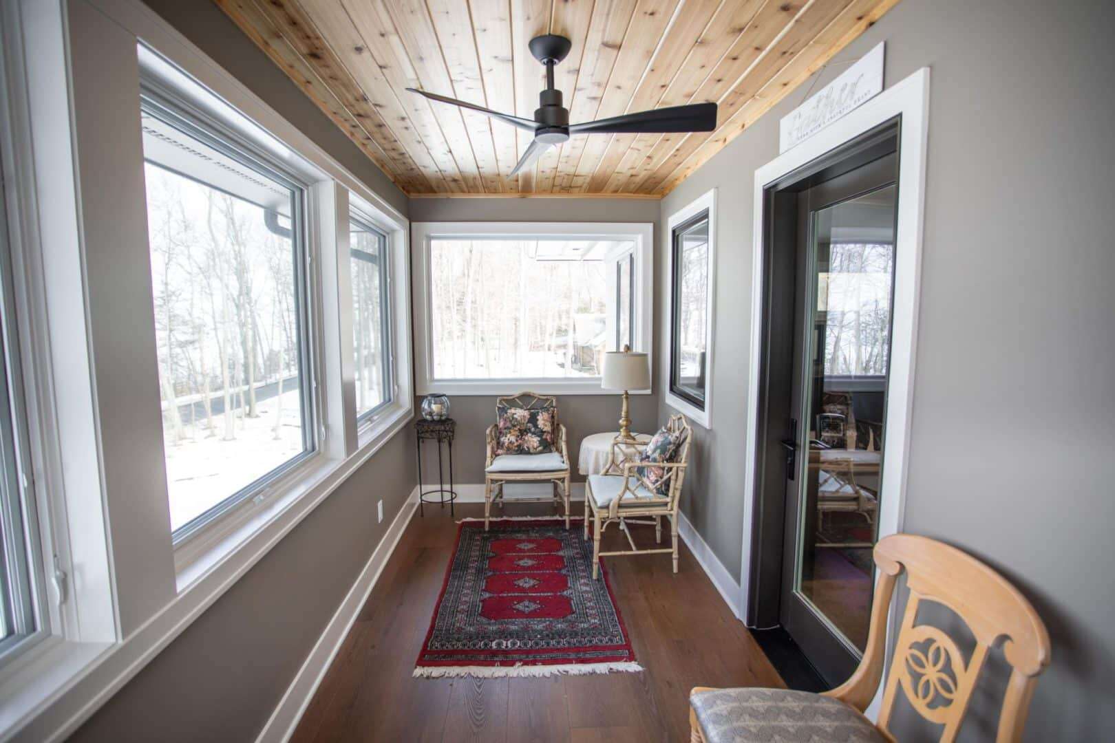 Sunroom with large windows and cozy seating by Livingston Homes.