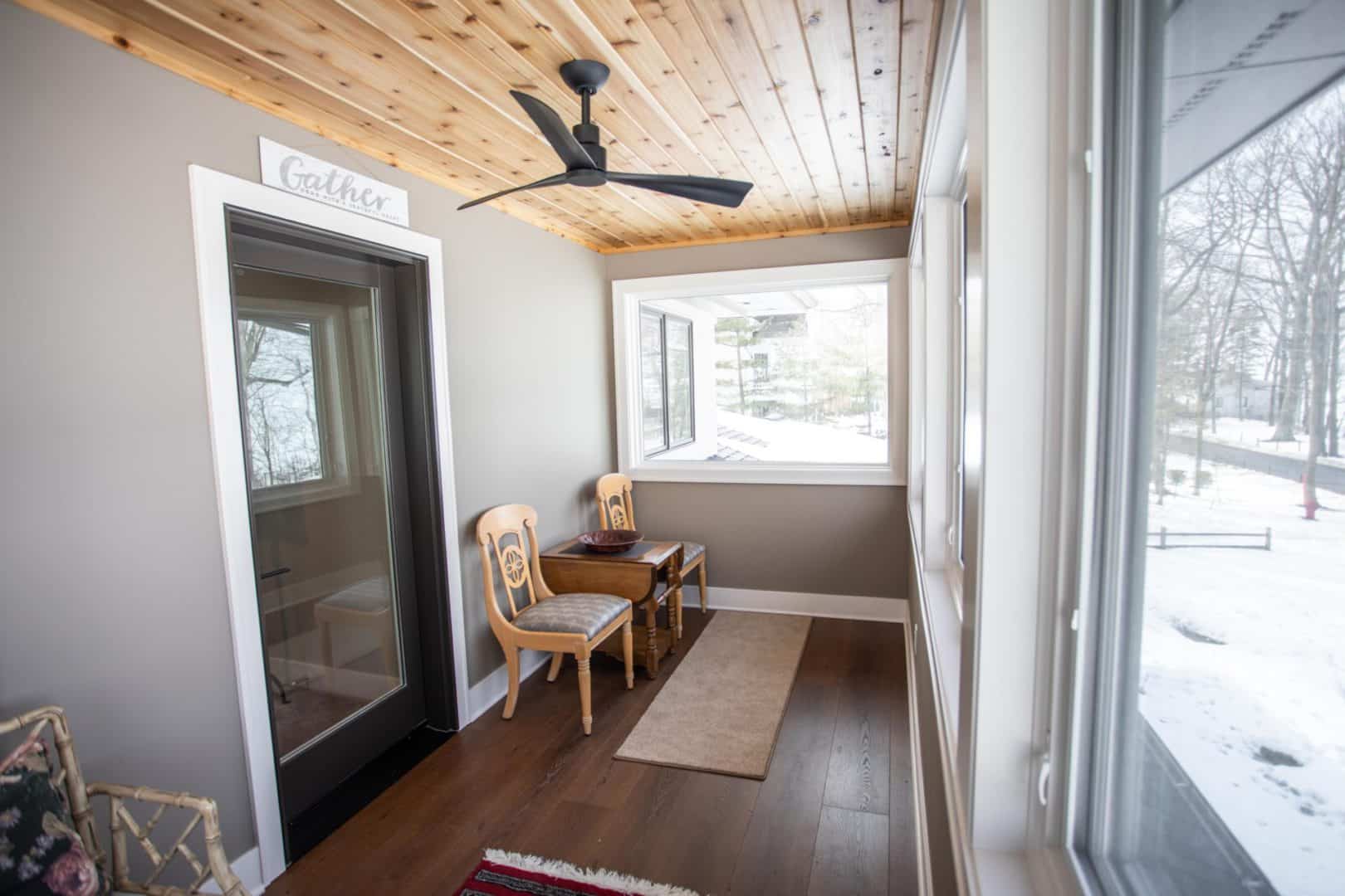 Sunroom with large windows and cozy seating area.