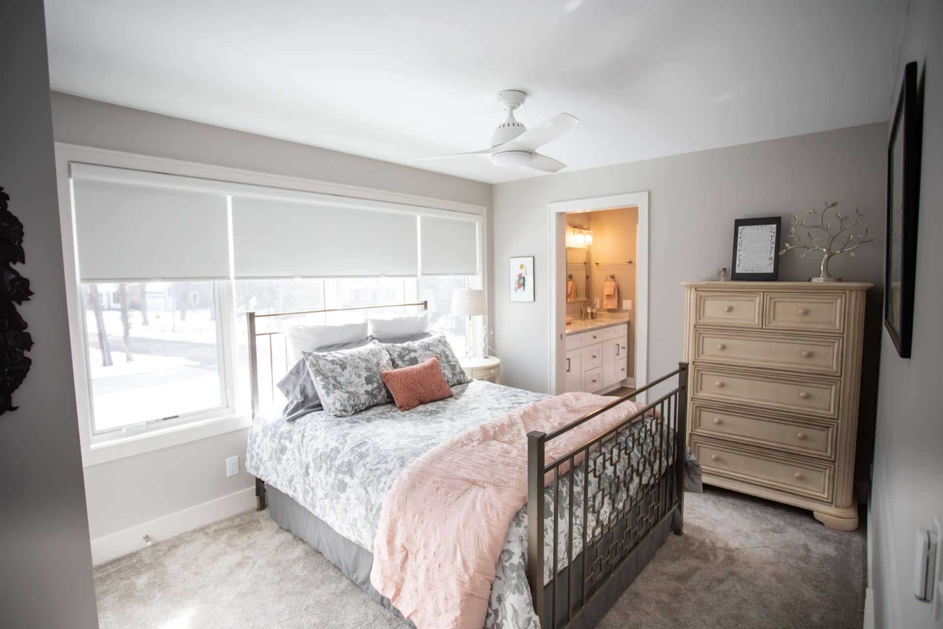 Bright bedroom with large window, cozy bedding, and stylish furniture in Livingston Homes residence.