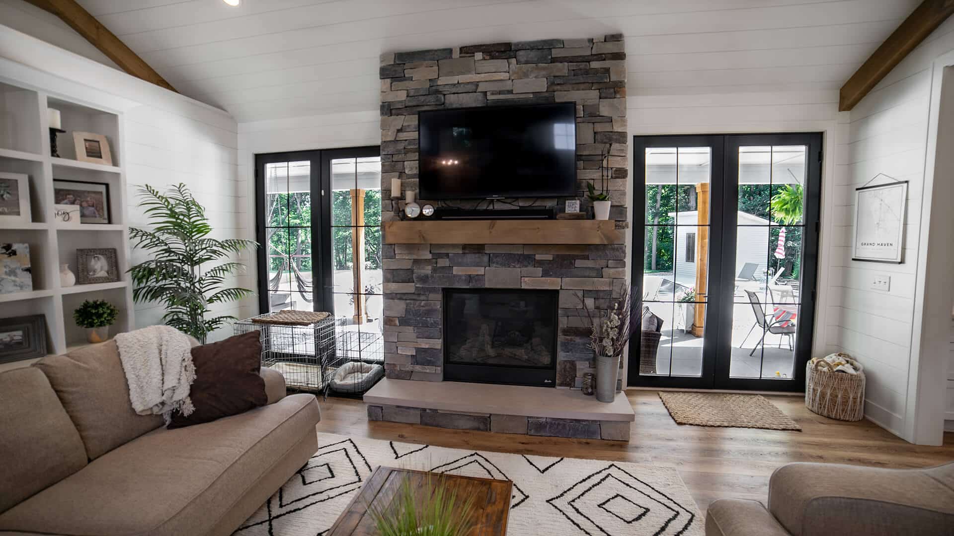 Living room with stone fireplace, large windows, and modern decor by Livingston Homes.