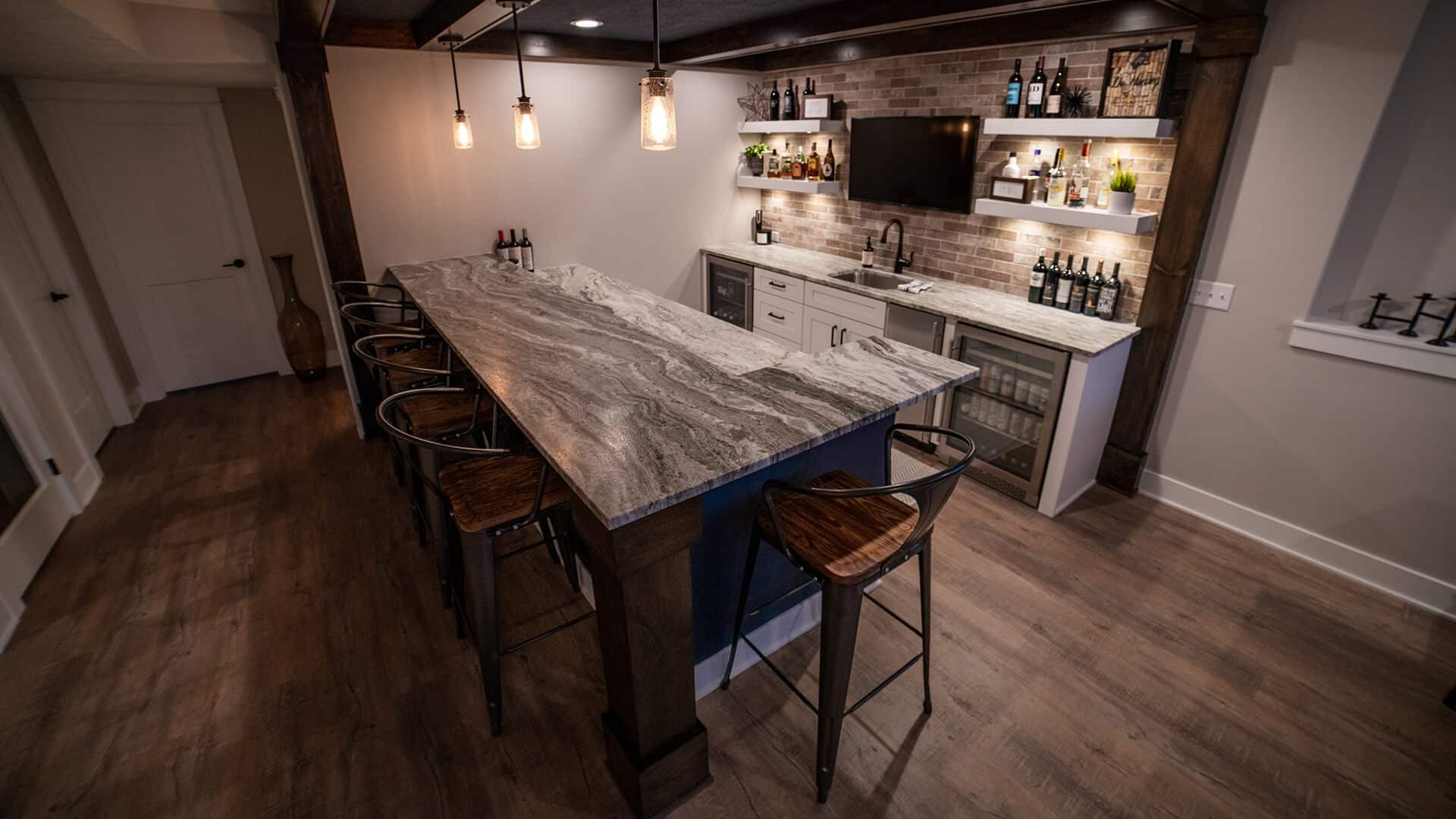 Home bar with marble countertop, ambient lighting, and beverage storage.
