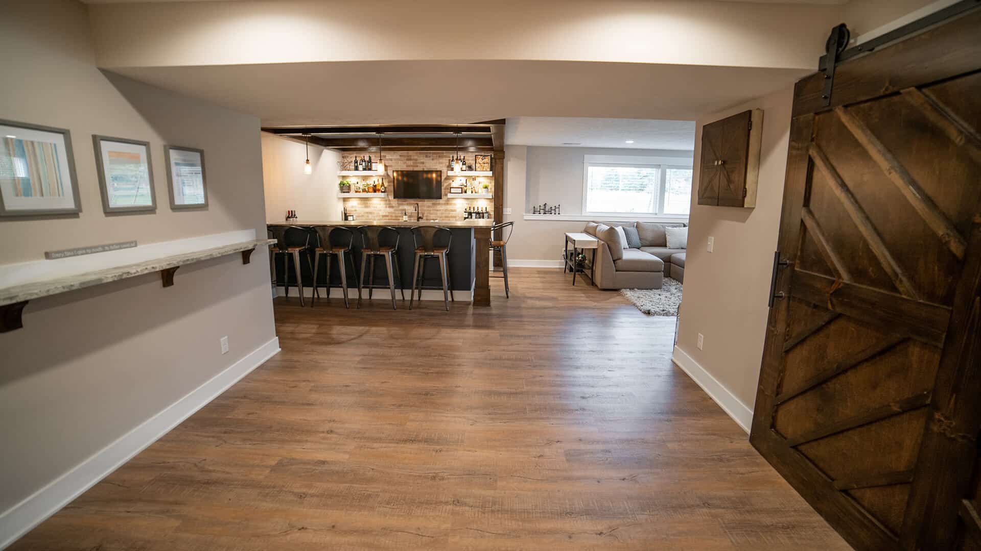 Spacious living room featuring a stylish bar area with seating, hardwood floors, and contemporary de.