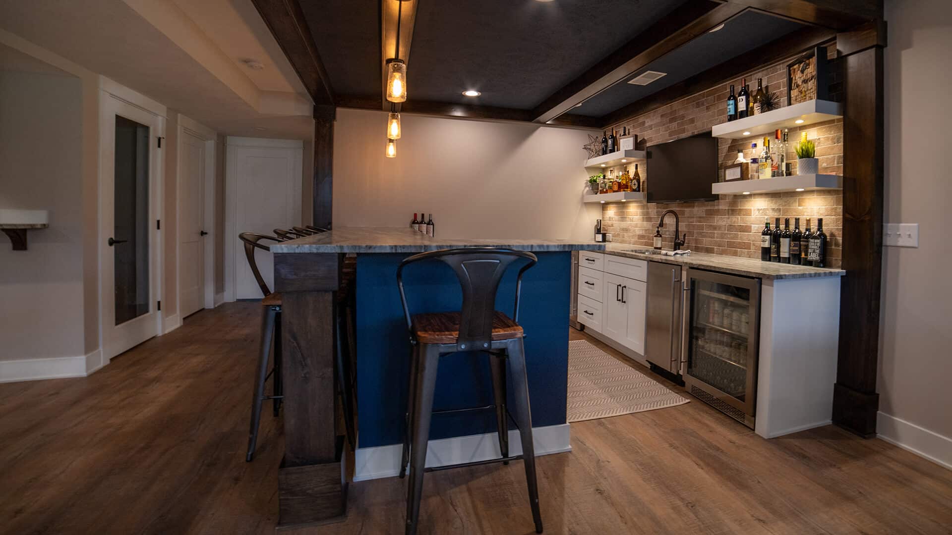 Modern kitchen with island, open shelving, and stylish lighting fixtures.