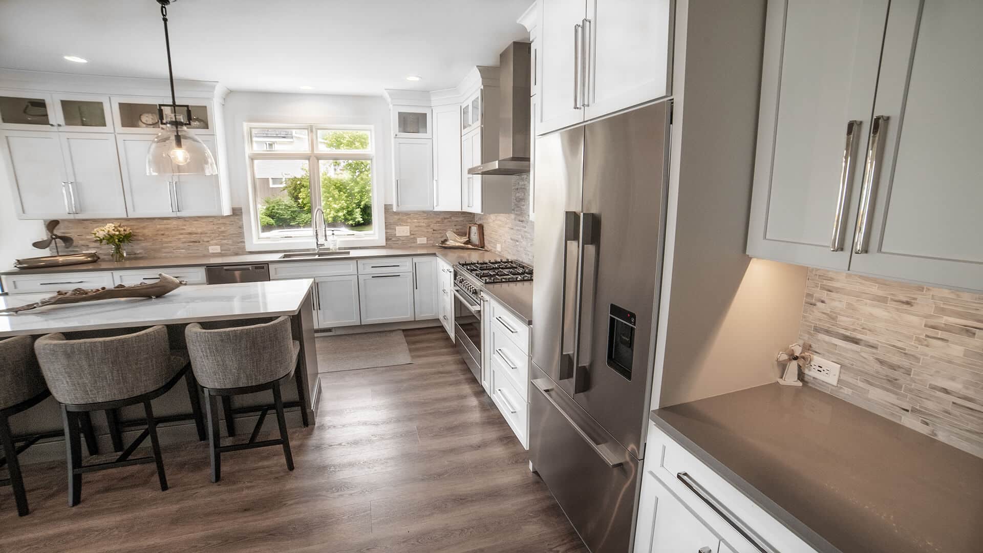 Bright modern kitchen featuring stainless steel refrigerator and oven, white cabinetry, and a spacio.